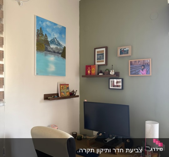 ציור נוף תלוי על קיר בחדר עבודה עם מחשב ושולחן עבודה
